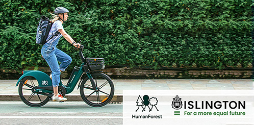 Young woman riding an ebike from Human Forest on the road, with helmet and rucksack.
